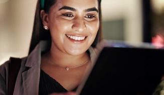 Mulher sorridente usando headphones e lendo um tablet, com foco na expressão feliz e conteúdo digital, promovendo o uso de tecnologia com Wi-Fi seja bem-vindo.